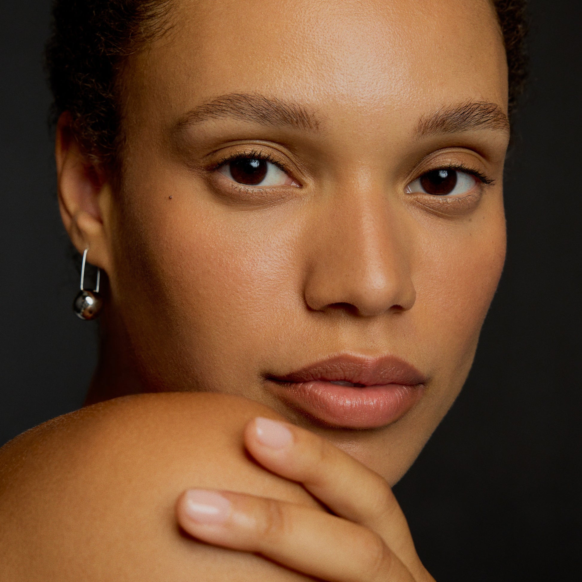Close-up of a woman with a neutral expression against a dark background